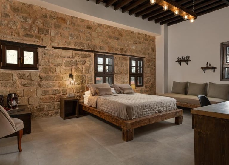 Rustic hotel bedroom featuring a natural stone wall, wooden platform bed, and industrial lighting.