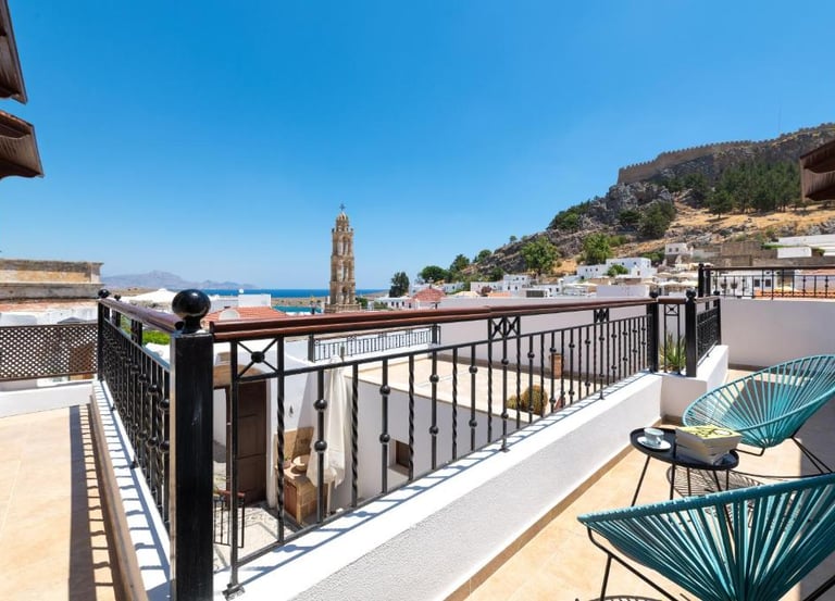 Luxury balcony in Lindos, Rhodes overlooking the historic village, church tower, and Acropolis.
