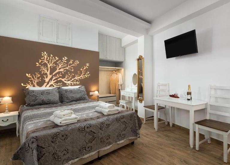 Modern boutique hotel bedroom with a tree wall decal, double bed, and dining area.