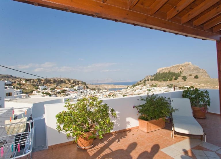Rooftop terrace overlooking Lindos village and the ancient Acropolis in Rhodes, Greece.