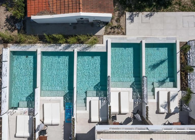 Aerial view of luxury apartment suites with private plunge pools and white sun loungers.