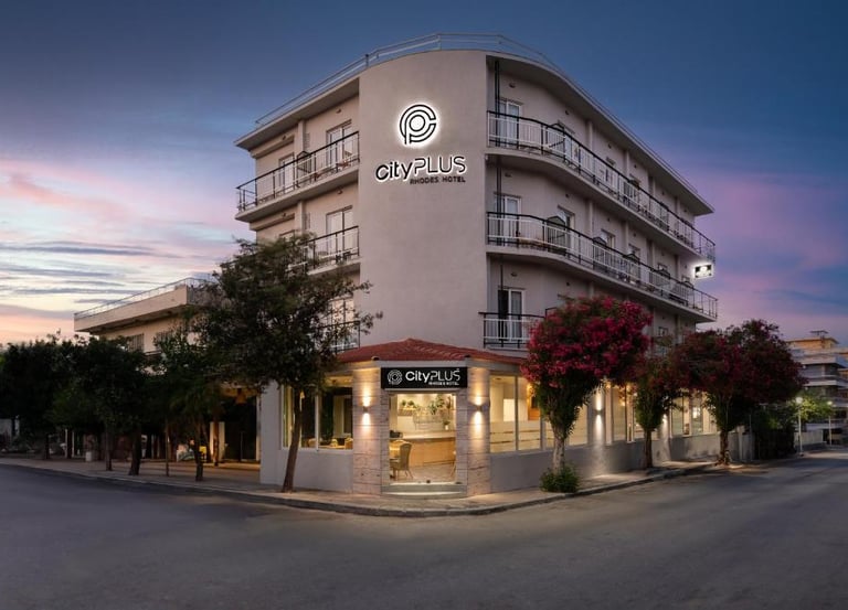 The exterior of City Plus Rhodes Hotel, a modern accommodation building at dusk.