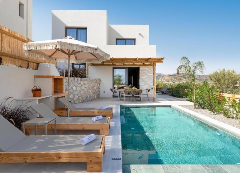 Modern luxury villa with private swimming pool, sun loungers, and outdoor dining patio.