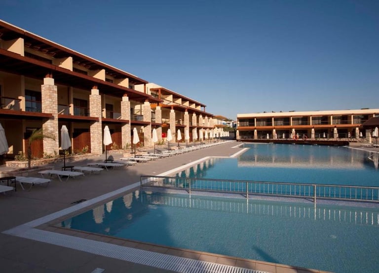 Luxury resort pool with lounge chairs and beach umbrellas near modern hotel buildings.