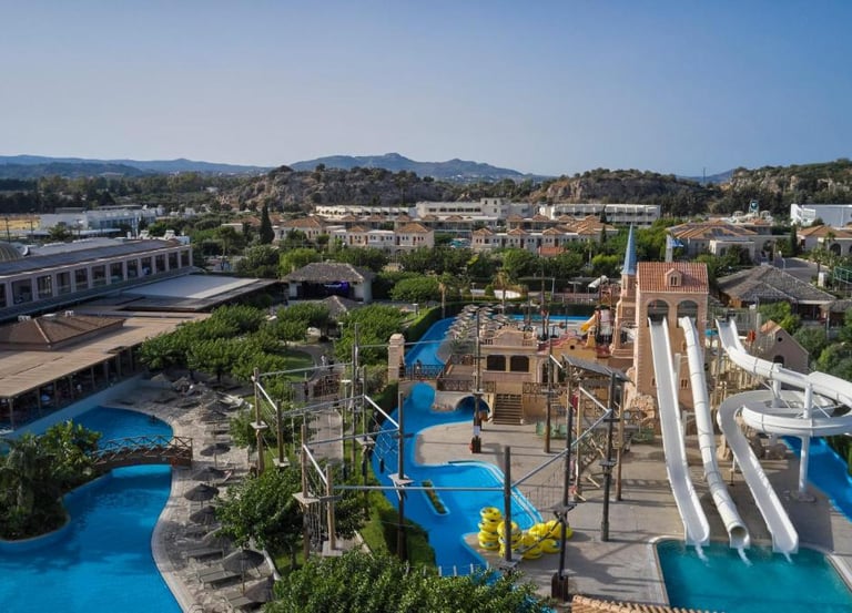 Aerial view of a family resort water park with white slides, swimming pools, and rope course.