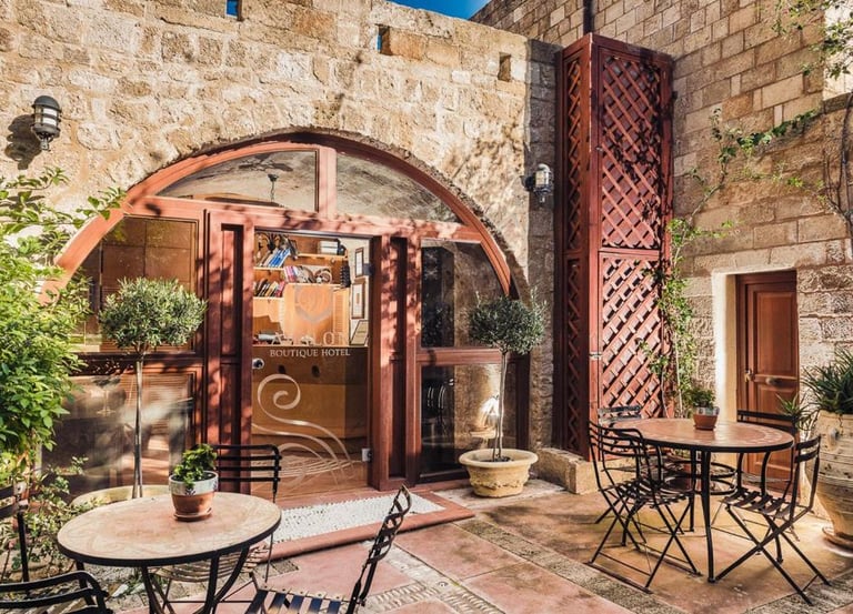 Rustic stone courtyard at Avalon Boutique Hotel featuring outdoor seating and arched glass entryway.
