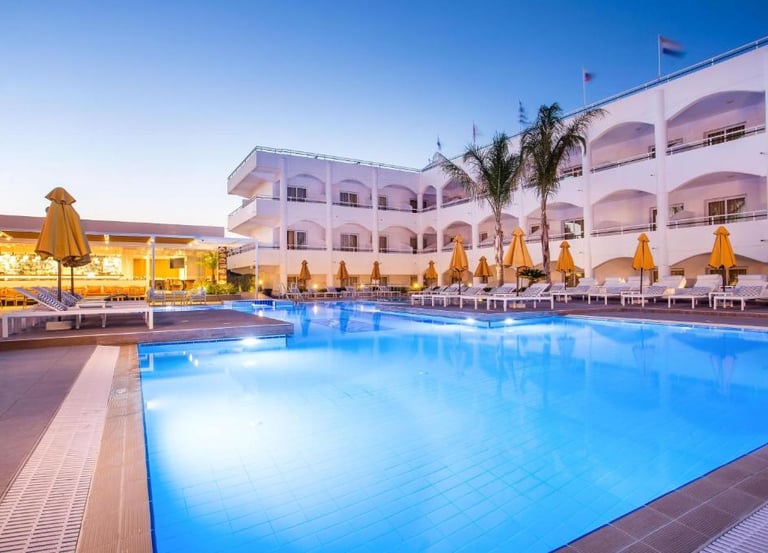 Luxury resort swimming pool with lounge chairs and palm trees at dusk.