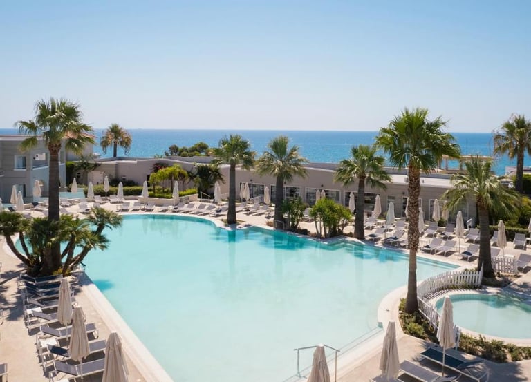 Luxury beach resort with a large swimming pool, palm trees, and ocean view.