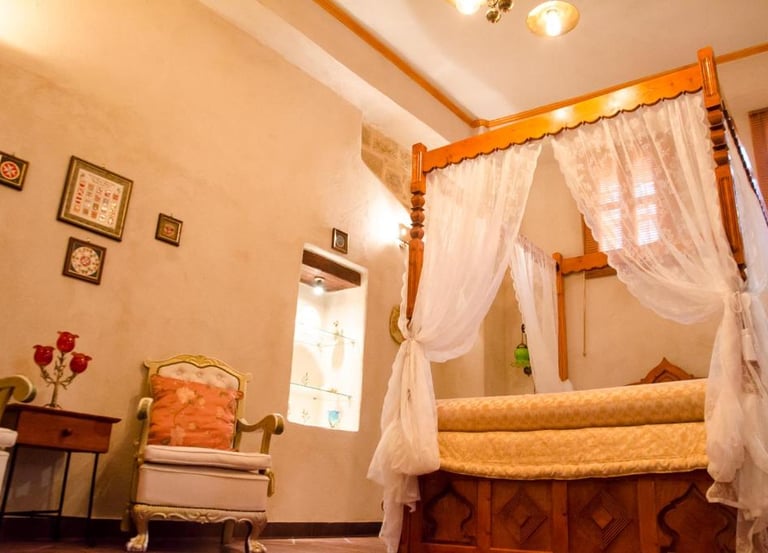 Elegant boutique hotel bedroom featuring a wooden four-poster canopy bed with white lace curtains.
