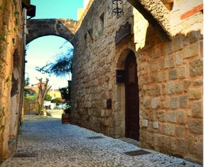 Historic stone alleyway in the Medieval City of Rhodes featuring cobblestone streets and stone arches.