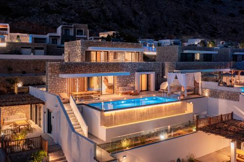 Luxury stone villas at night featuring an illuminated private infinity pool and modern patio.