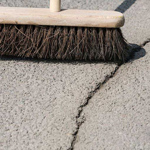 Sweeping asphalt in preparation for crack repair