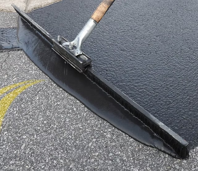 Spreading sealcoat on parking lot repair