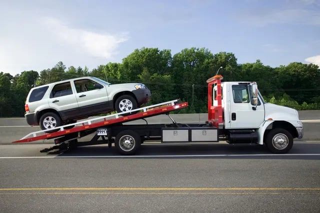 a tow truck with a junk car being towed for cash