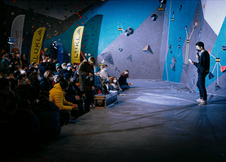 a man standing near a climbing wall in front of a crowd