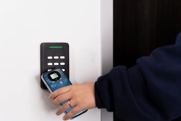 Person unlocking door using smartphone with Apple Wallet and NFC-enabled access control system from UniFi