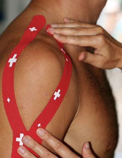 Sports Therapist applying tape to a client's shoulder