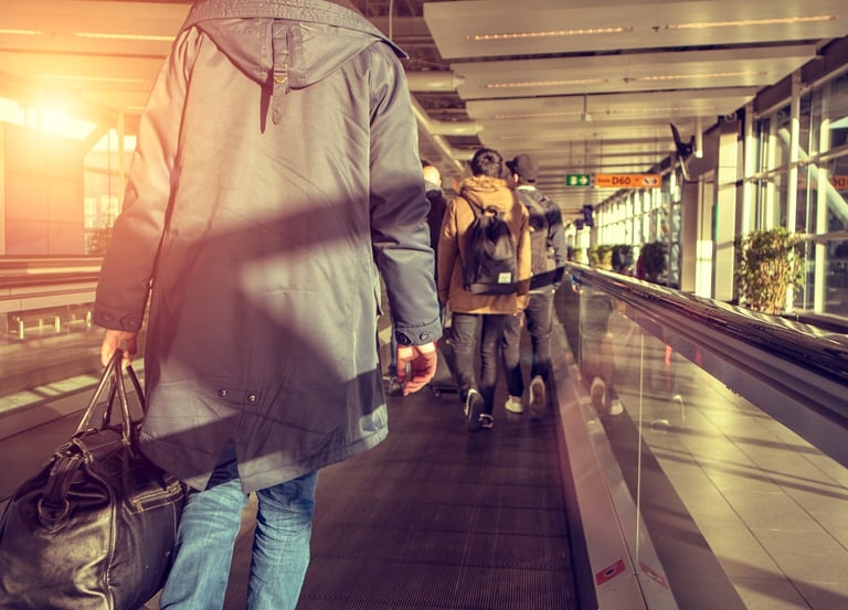 A line of travellers carrying bags queues at an airport check-in