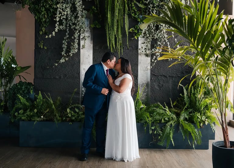 Retrato elegante de novios recién casados dándose un beso en entorno estético de plantas en Quito