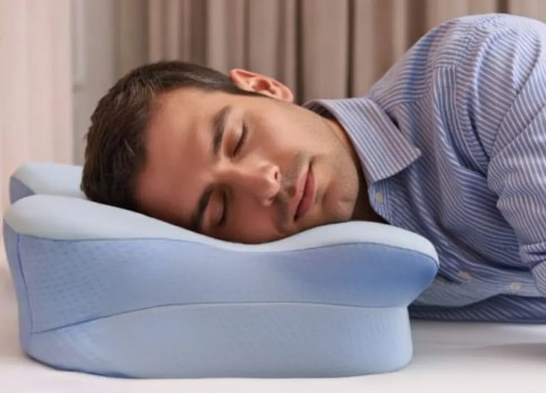 Man sleeping on his side with an ergonomic contour pillow for head and neck support.