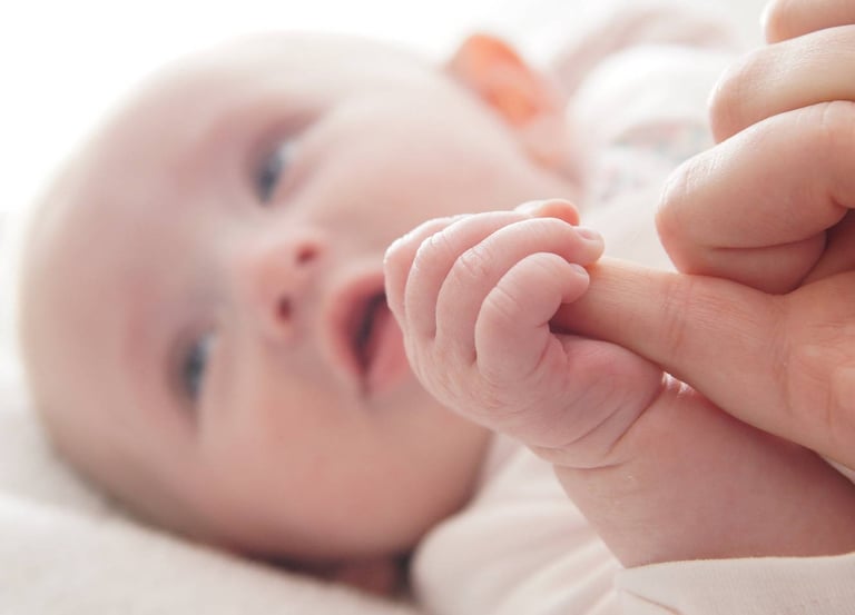 Gros plan sur la main de bébé serrant le doigt de sa mère. Portrait doux de nouveau né.