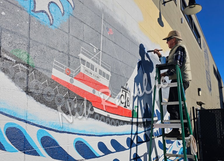 Man on a stepladder painting a mural of a tugboat on a wall