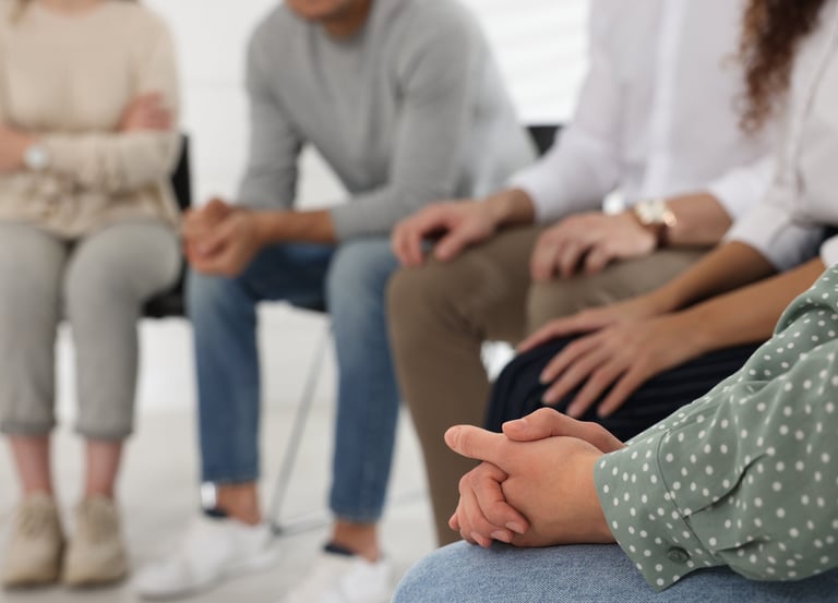 a group of people sitting in a circle with their hands clasped together