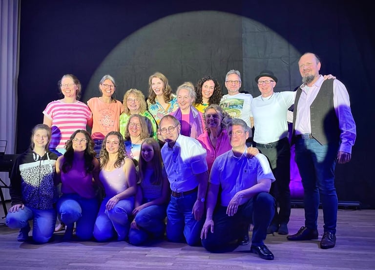 ein Gruppenfoto von knapp 20 freudigen Personen auf einer Bühne im Spotlight