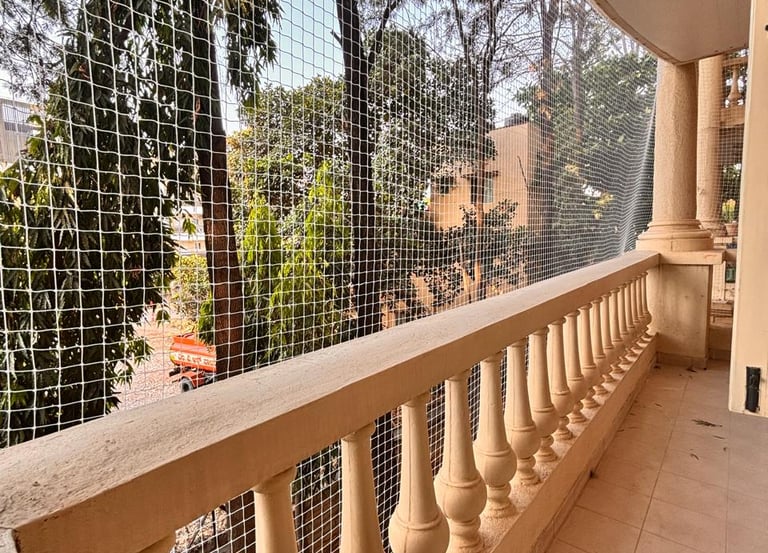 A technician carefully installing a strong safety net on a residential balcony under bright daylight