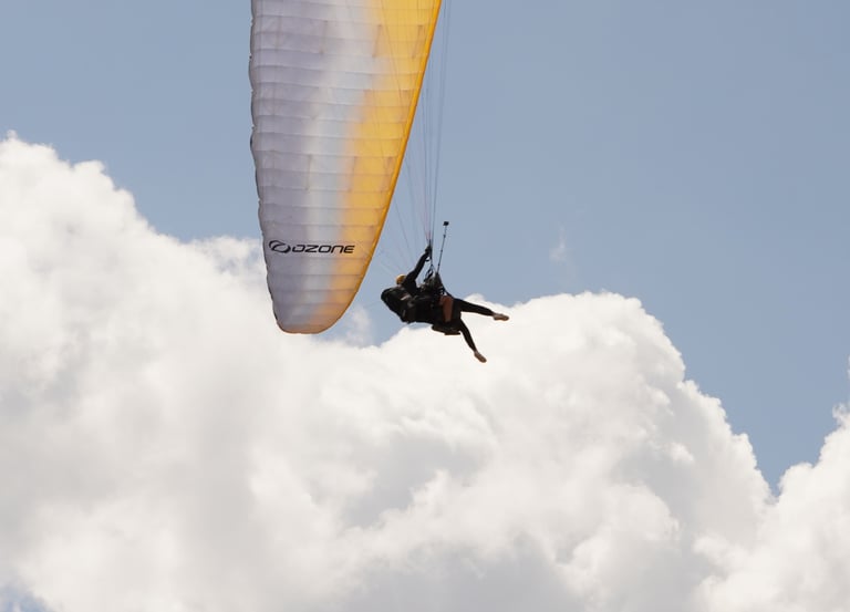Pilota in volo con parapendio sopra le nuvole, esperienza di volo libero nella natura vicino a Rieti