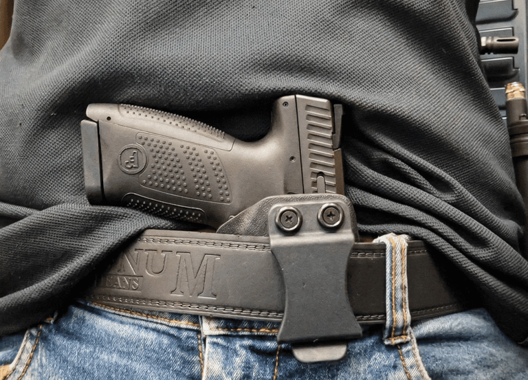 Black handgun in an IWB kydex holster for concealed carry on a leather belt.