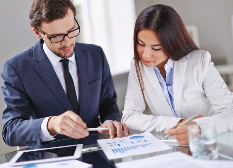 Professional business colleagues analyzing financial data charts and marketing reports in a bright office.