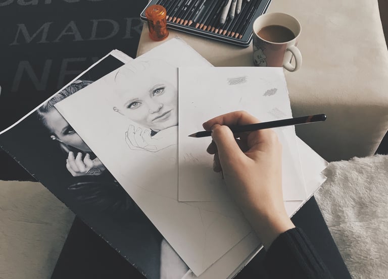 A person holding pen on top of the drawing paper