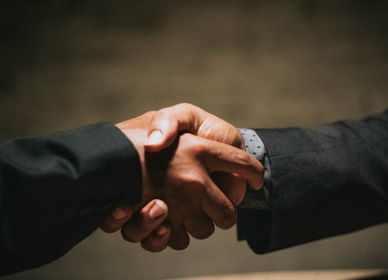 two people shaking hands over a wooden table