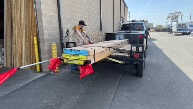 a man is loading a carton of wood planks
