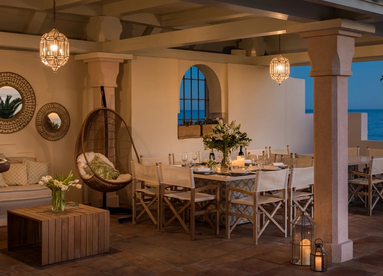 Covered outdoor dining terrace with lantern lighting and sea views