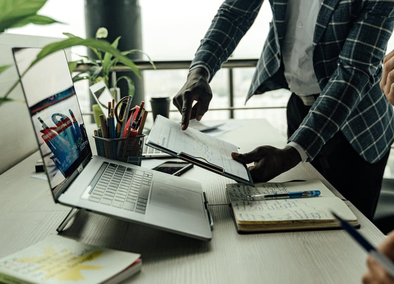 a man in a suit and tie is standing at a desk with a laptop