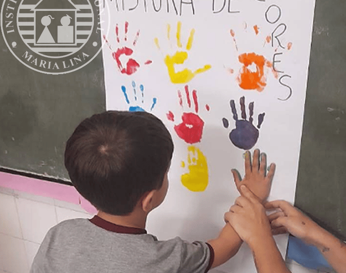 Aluno realizando atividade de pintura com as mãos