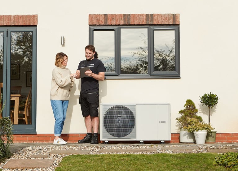 a man and woman in front of a outside heat pump