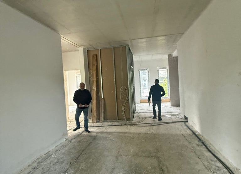 Zwei Bauarbeiter in einem unfertigen Raum mit offener Tür – Baustellenszene im Innenausbau