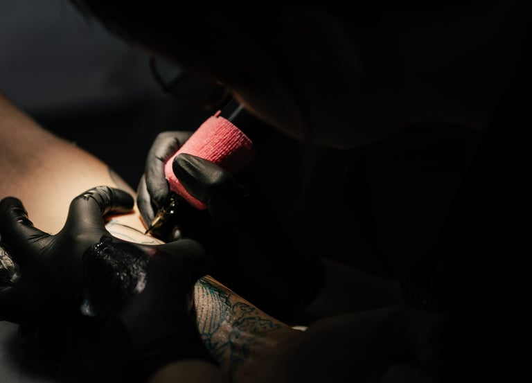 Photo d'une séance de tatouage ou l'on voit les mains de la tatoueuse tenant le dermographe 