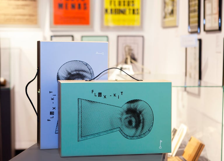Two coloured FluxKit suitcases: green and blue. They feature a keyhole and a peeking eye. 