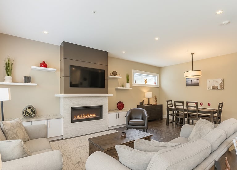 Modern open concept living room featuring a gas fireplace, wall-mounted TV, and adjacent dining area.