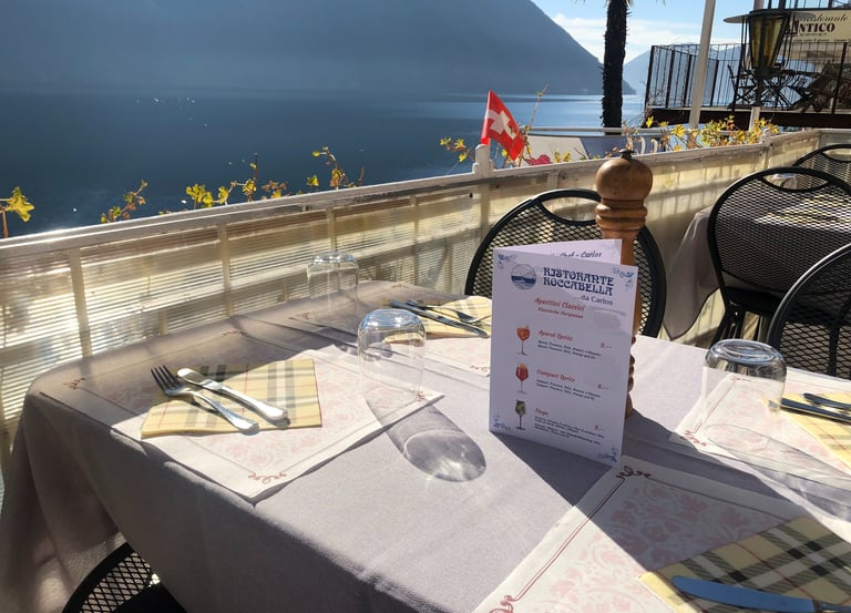 Un tavolo apparecchiato con vista sul lago di Lugano e un menu
