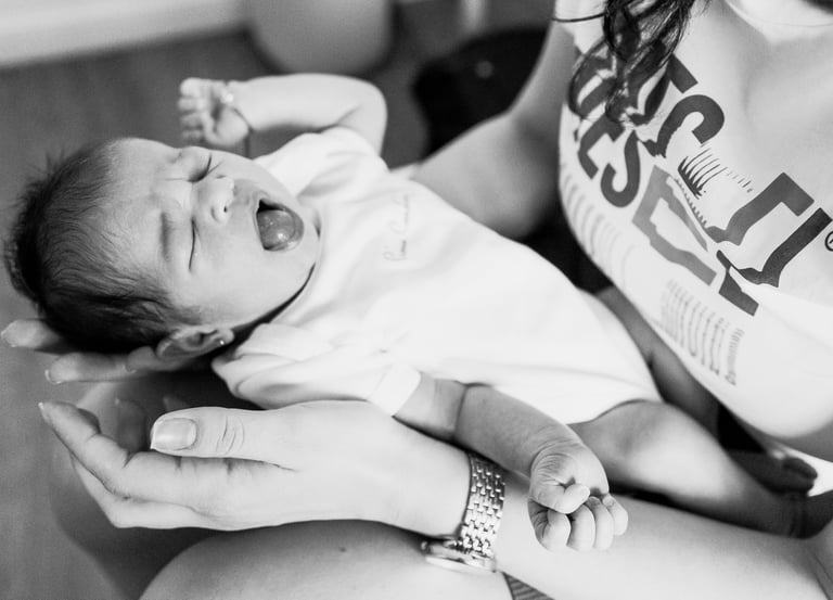 a mother is holding a baby in her arms while the baby yawns