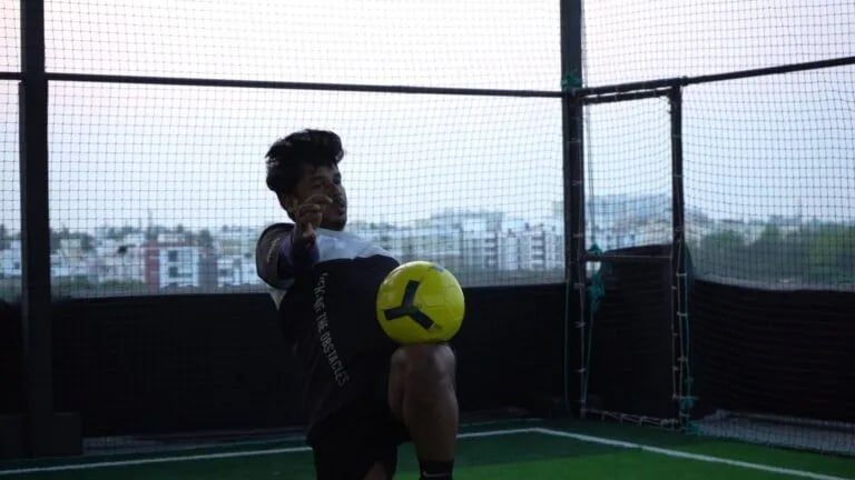 a man holding a soccer ball in a cage