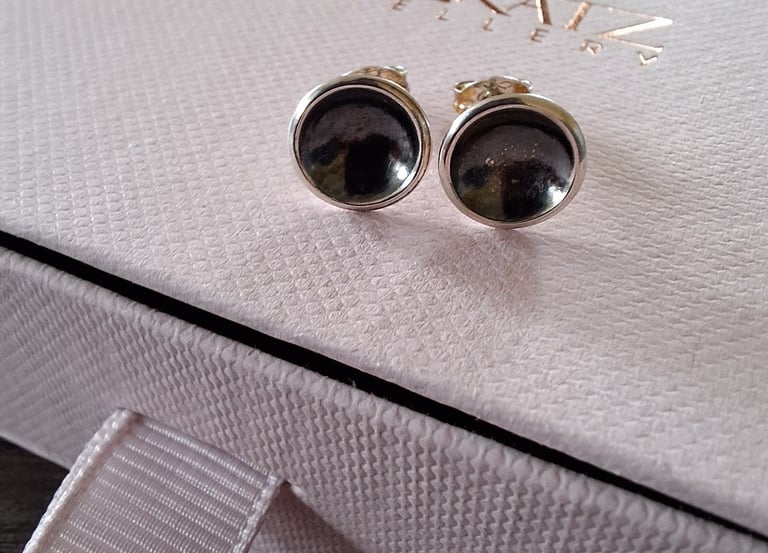 Handmade silver stud earrings with dark circular inserts on a pink Lisa Katz Jewellery box.