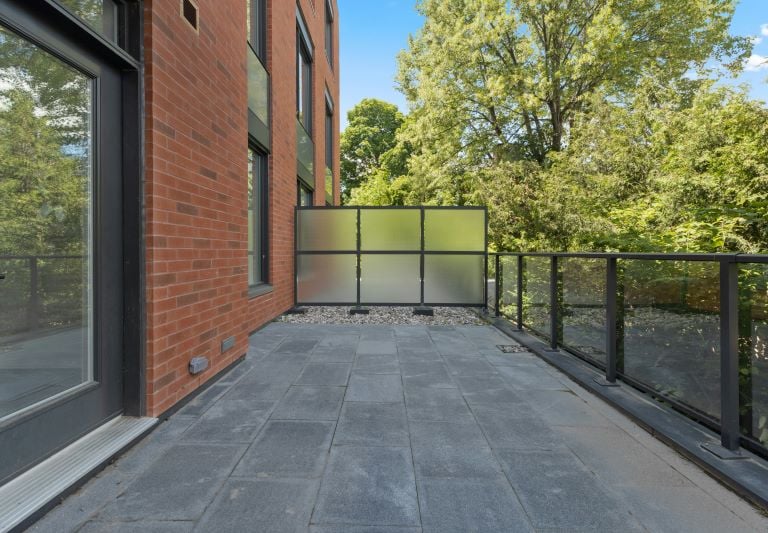 einen Balkon mit einem Glasgeländer und einer Glastür