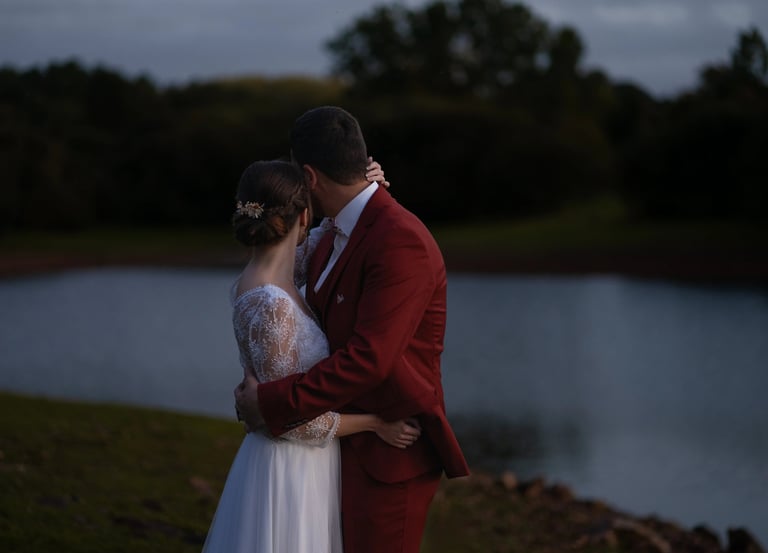 Des mariés s'embrassant au bord d'un lac au crépuscule lors d'un mariage