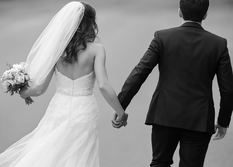 a bride and groom holding hands and walking down a path